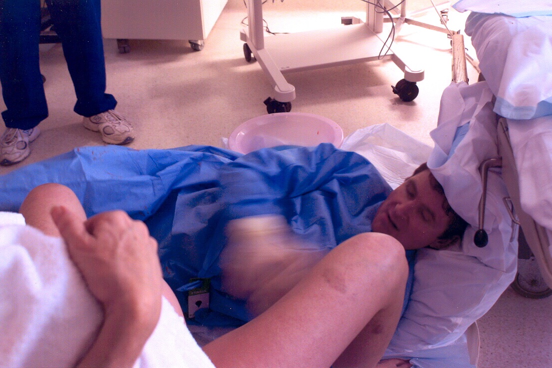 Obstetrician lying on floor and using obstetric bed for head support