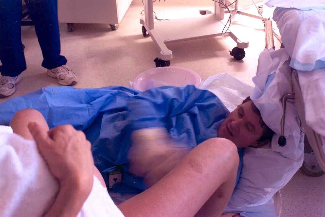 Obstetrician lying on floor and using obstetric bed for head support